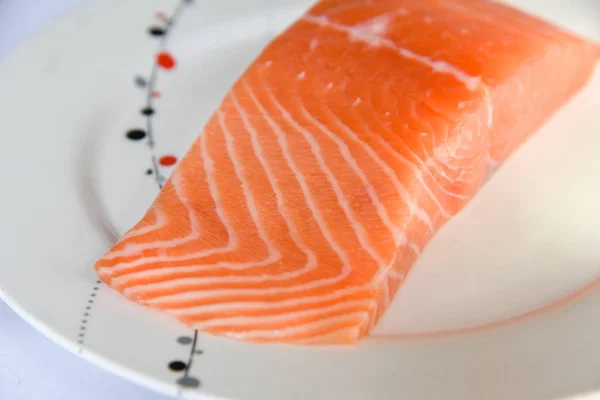 Salmon in white dish on white blackground.