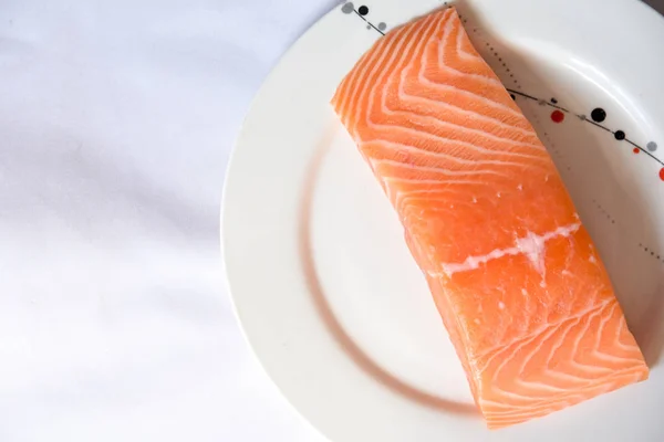 Salmon in white dish on white blackground.