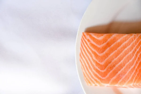 Salmon in white dish on white blackground.