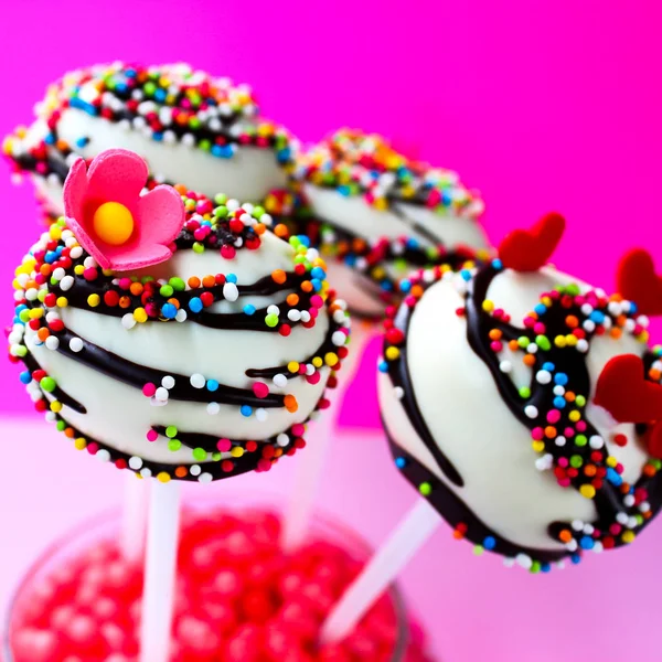 Colorful cake pops on a pink background