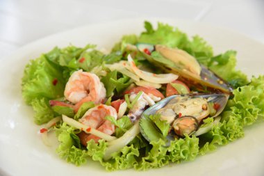 bir restoranda masada domuz eti ve kabuklu deniz ürünleri ve kalamar ile baharatlı salata