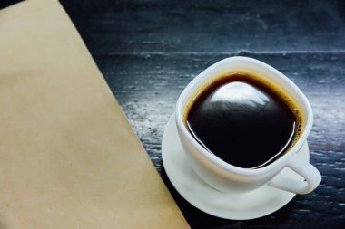 Bardakta espresso ve siyah ahşap masada defter.