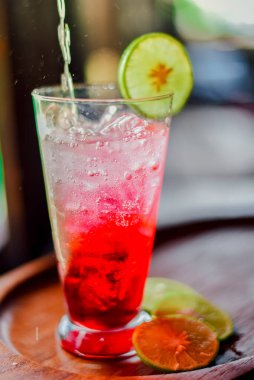 Kafe 'deki ahşap masada kırmızı meyve suyu, balina suyu ve limon. Yaz içeceği