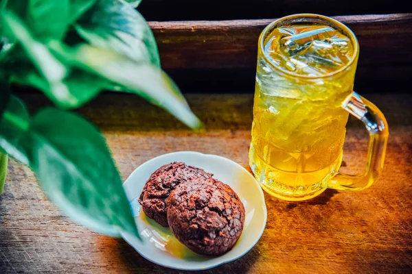 Chinese Chrysanthemum Tea in tall glass and  Brownie cookies on wood table, health herbal tea.