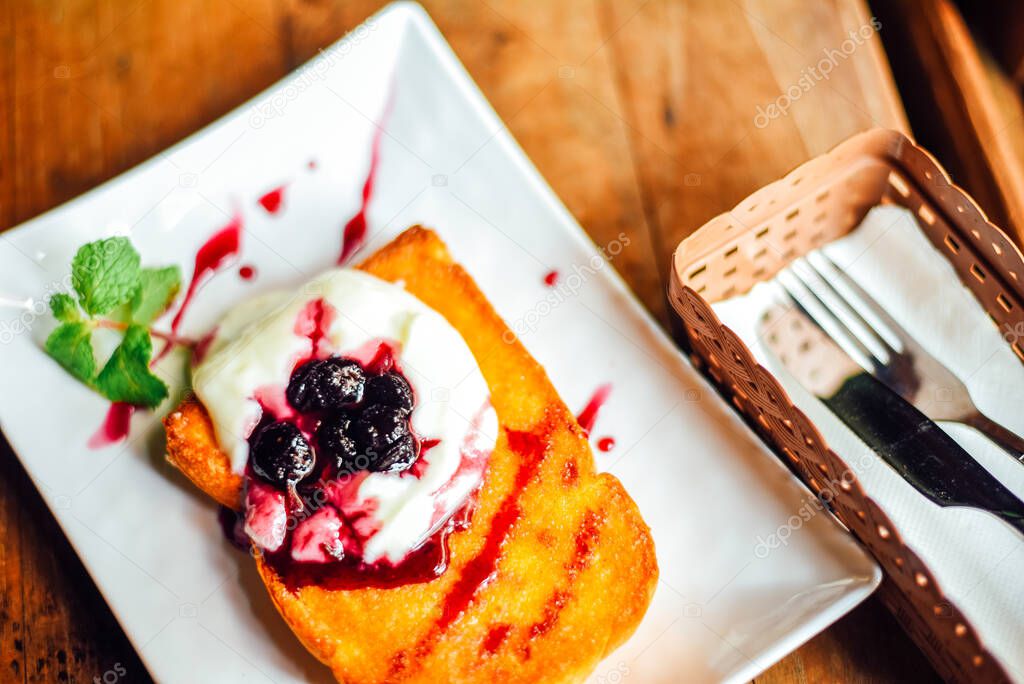 Toast with Yogurt , blueberry and  honey  in  white plate on  wooden table, Breakfast baked