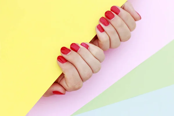 Manicure vermelho em fundo multi-colorido . — Fotografia de Stock