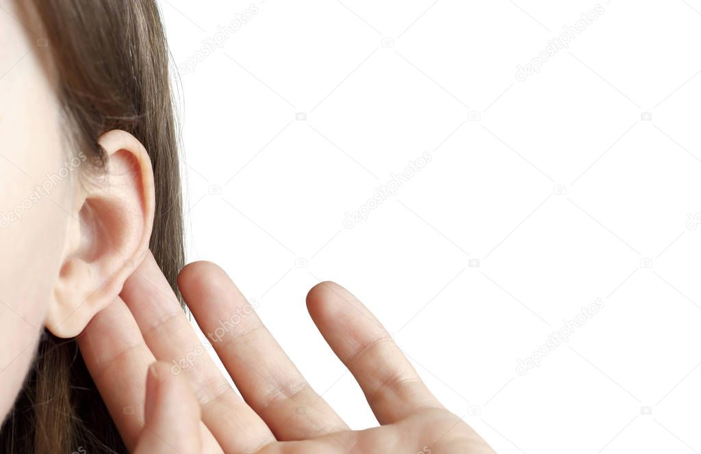 The girl listens attentively with her palm to her ear, close-up isolated on white background, indoors, the news concept