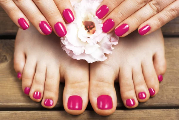 Pink manicure and pedicure with flower close-up, isolated on a w