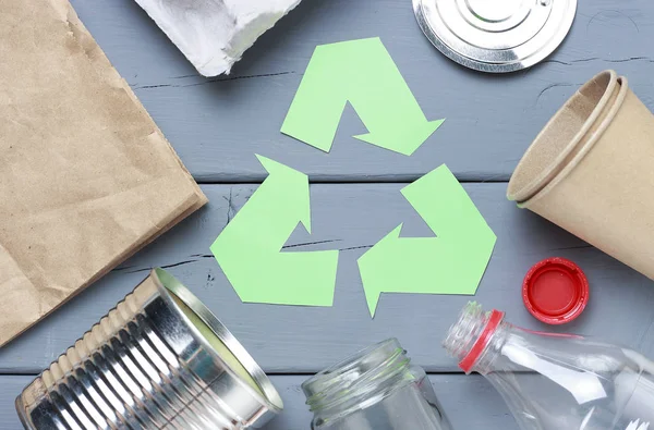 Un verde reciclar el símbolo de la basura y el plástico, la basura de hierro sobre un fondo gris, vista superior . — Foto de Stock