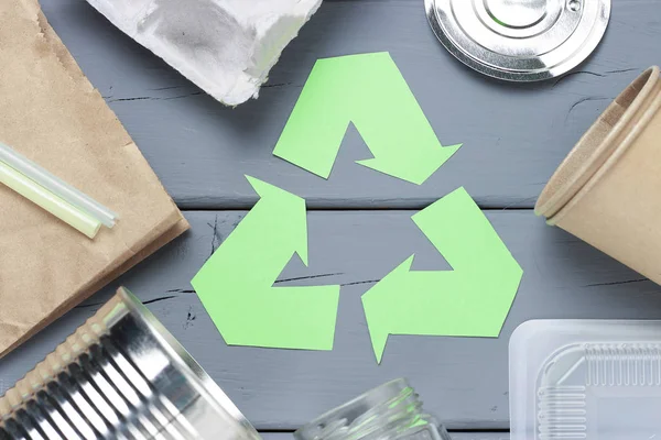 Zelený symbol recyklace a plastický odpad, železné smetí na šedém pozadí, pohled shora. — Stock fotografie