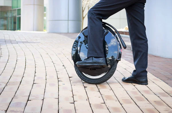 office worker is driving on an electric mono wheel, side view
