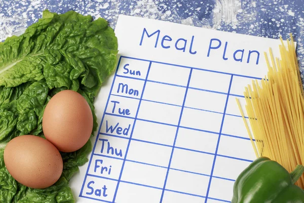 Inscription Meal Plan, schedule on white sheet and salad. View from above