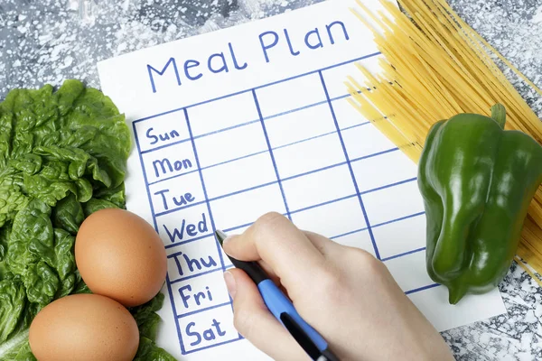 Inscription Meal Plan, schedule on white sheet and whriting hand. View from above