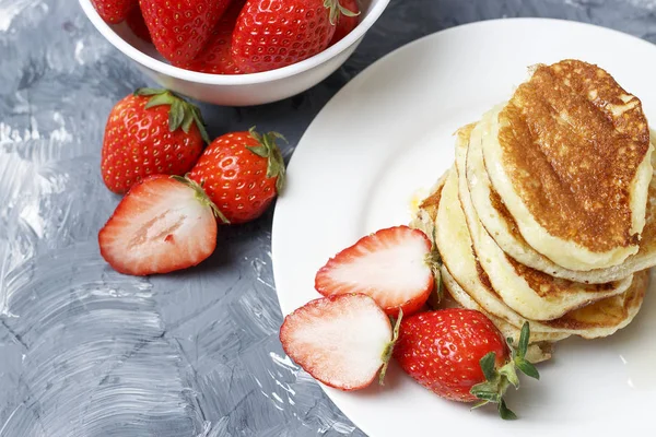 Pfannkuchen auf Teller und Erdbeeren auf grauem Hintergrund — Stockfoto