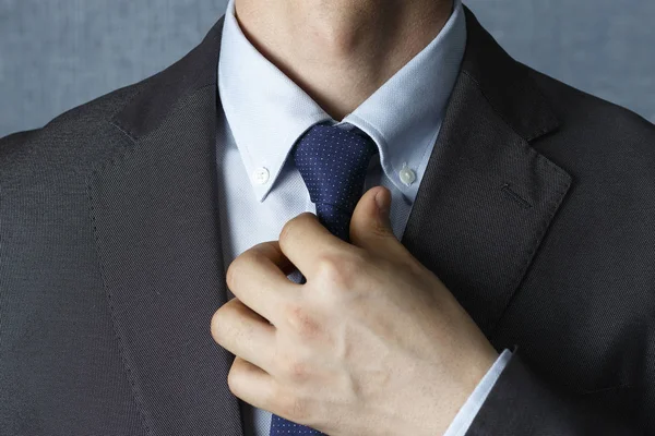 Man in suit straightens tie close-up, front view