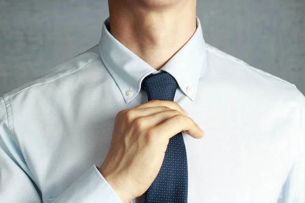 Man in suit straightens tie close-up, front view