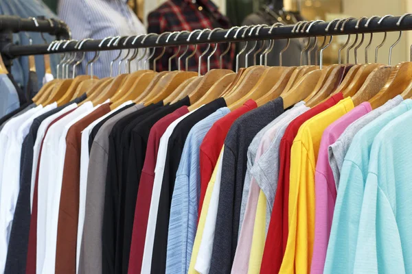 Разноцветные футболки с длинными рукавами на деревянных вешалках, вид сбоку . — стоковое фото