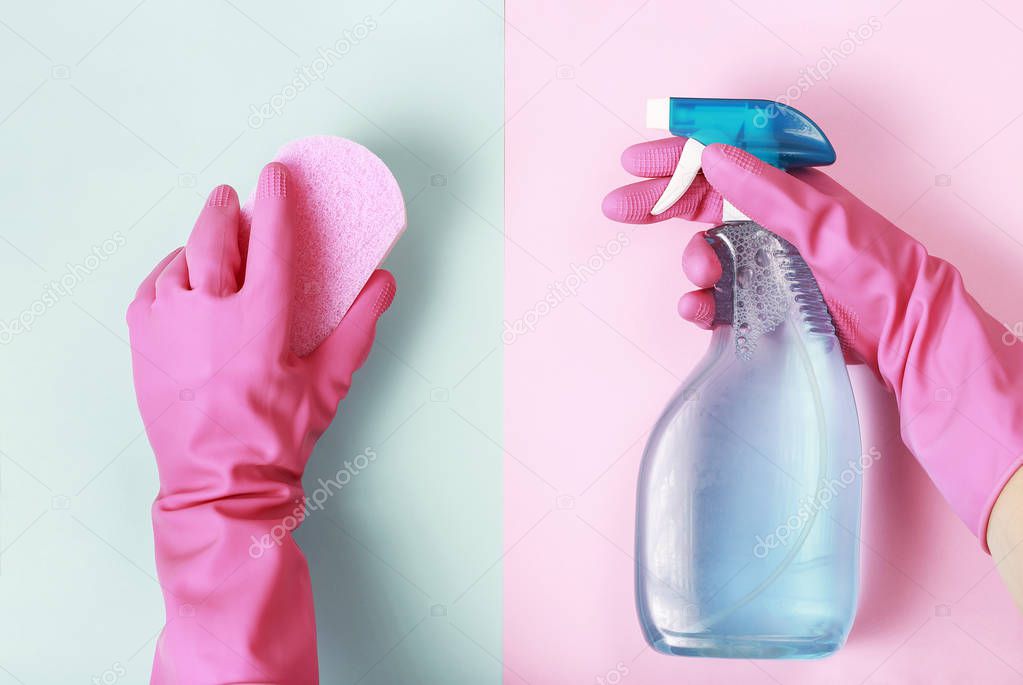 Female hands in glove holds window spray and sponge on pink and blue background, top view, spring cleaning concept