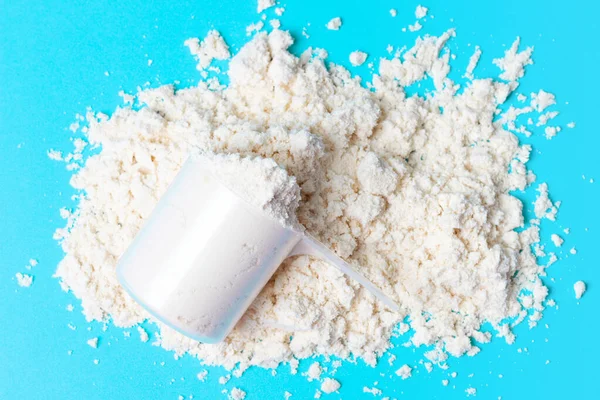 Scattered protein in scoop on a blue background top view