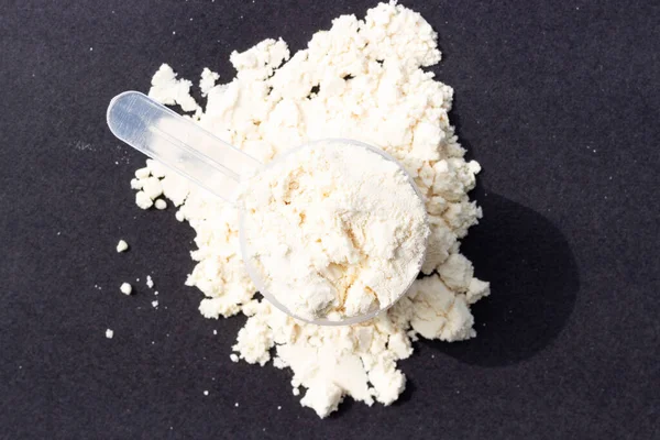 Scattered protein in scoop on a black background, top view