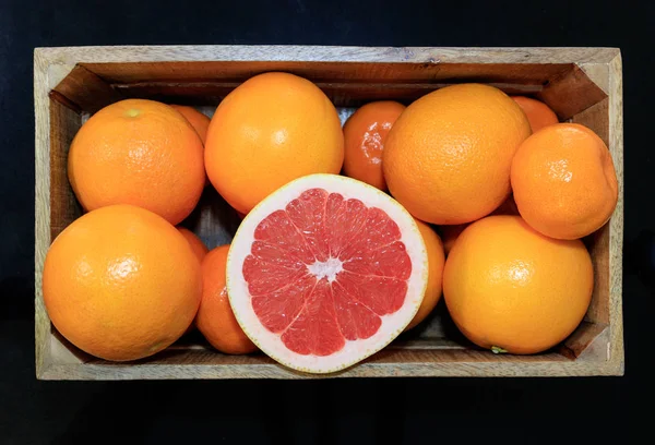 Sliced Ruby Red Grapefruit on top of oranges and mandarins. Fresh citrus fruit.