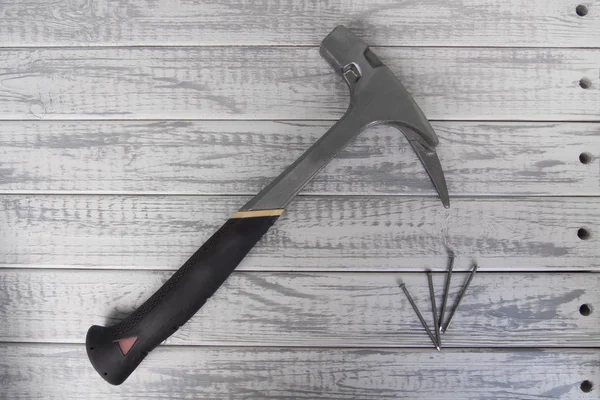 Hammer of carpenter or roofer and several nails on grey wooden background — Stock Photo, Image