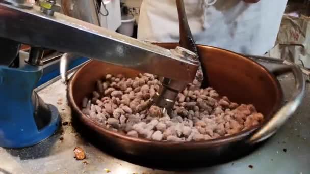 Cacahuetes caramelizados, almendras en brasero, manos rociando azúcar en el puesto de la calle — Vídeos de Stock