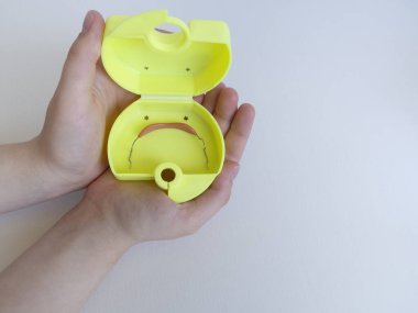 Ergen ellerinin ya da avuçlarının içinde ortodontik aygıt, metal ve plastik diş telleri bulunan yeni sarı kutular olan açık avuçlar, diş telleri, diş telleri, çocuklar, çocuklar ve gençler için kullanılır. Boşluğu kopyala.