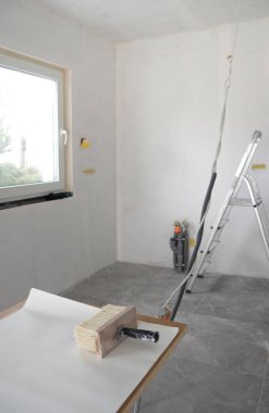 Geniş boya fırçası tutkal için ahşap tabanlı fırça, masa üzerine beyaz duvar kâğıdı serpiştirilmiş pencere, merdiven, arka planda gri fayanslar ile yenileme odasına yapıştırmak için. Kopyalama alanı.