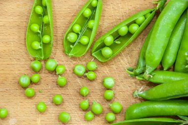 Sepet, ahşap tahta üzerinde tatlı yeşil bezelye taze bakla