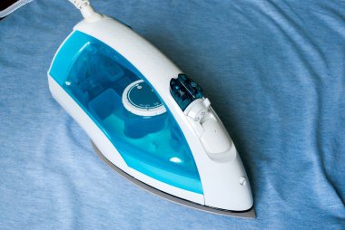 Ütü tahtasında elektrikli demir ve gömlek.