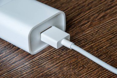 Beyaz elektrikli usb kablosu ve şarj cihazı fişi duvar çıkışında.