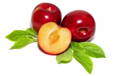 Yeşil yapraklı erik meyveleri ve beyaz üzerine izole edilmiş dilimler..