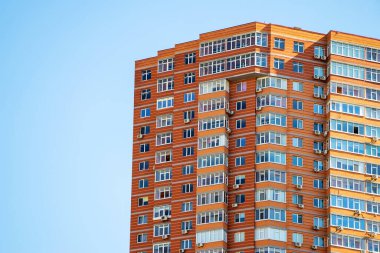 Gökyüzü arka planında pencereleri olan tuğla bina.