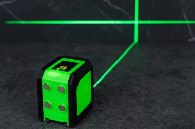 Bloklardan bir duvar inşa ederken lazer seviyesi. İnşaat alanlarındaki hatları ve seviyeleri belirlemek için lazer seviyesi tamamlanmamış beton bloklardan yapılmış bir duvarın üzerinde duruyor..