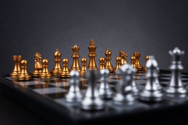 Tahta satranç tahtasına altın ve gümüş satranç figürleri yerleştirildi. İş hayatında entelektüel düello ve taktiksel savaş. Strateji planlaması, liderlik ve takım çalışması kavramı.