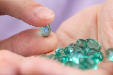Man's hand holding blue gel capsule Close up.