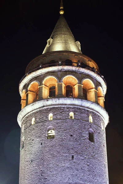 Galata Kulesi Istanbul Türkiye'de karşı siyah gece gökyüzünde parlıyor.