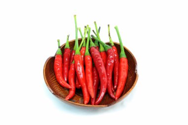 Beyaz arka plan üzerinde ahşap tabak içinde birçok kırmızı biber.