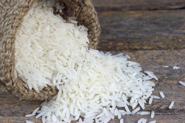 Pişmemiş Tayland yasemin pilavı, küçük kenevir çuvalına doldurulmuş, ahşap bir tahtaya dökülmüş..