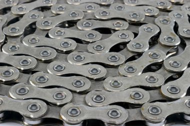 Titizlikle düzenlenmiş bir bisiklet zinciri zarif bir şekilde el değmemiş beyaz arka planda duruyor..