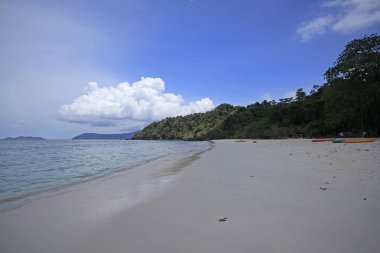 Deniz, plaj, dağ ve gökyüzü parlak bir günde.