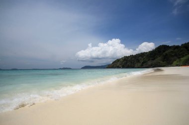 Deniz, plaj, dağ ve gökyüzü parlak bir günde.