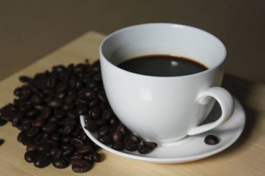 Kahve çekirdekleri, beyaz kahve bardağı ahşap üzerine yerleştirilen