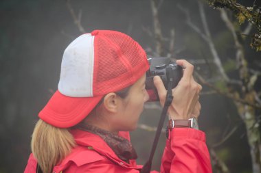 Kırmızı tişörtlü bir kadın fotoğraf çekiyor..