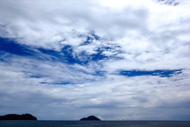 Parlak bir gökyüzünde dağlar ve deniz