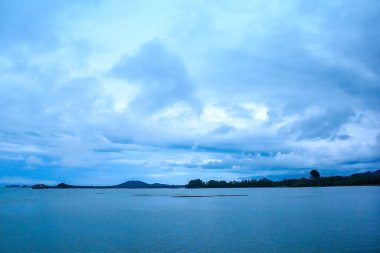 Denizdeki dağlar ve mavi gökyüzündeki bulutlar