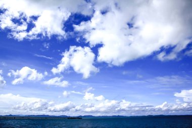 Denizdeki dağlar ve mavi gökyüzündeki bulutlar