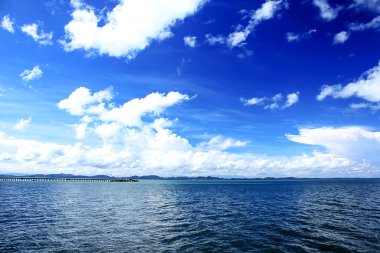 Denizdeki dağlar ve mavi gökyüzündeki bulutlar