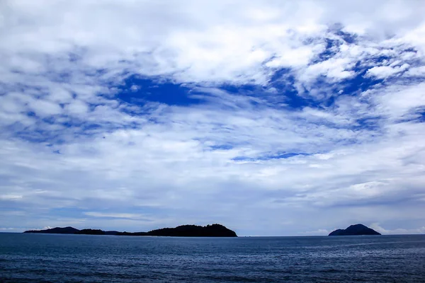 Denizdeki dağlar ve mavi gökyüzündeki bulutlar
